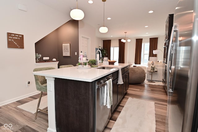 3110 W New York St, Indianapolis, IN 46222 - kitchen with appliances with stainless steel finishes, light countertops, a breakfast bar, dark wood-style floors, and a center island with sink