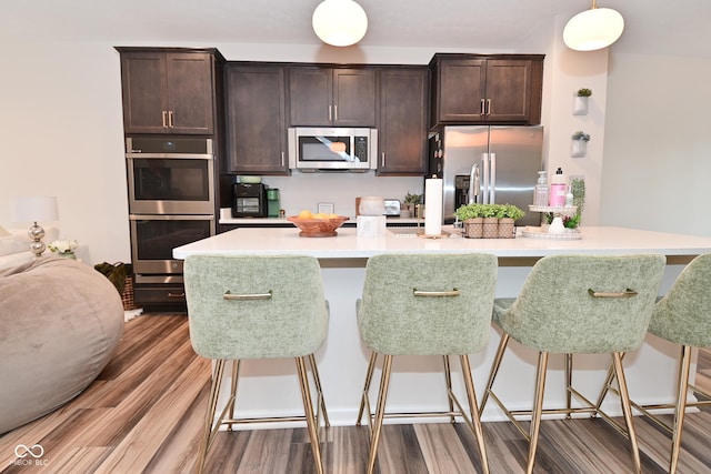 3110 W New York St, Indianapolis, IN 46222 - kitchen featuring appliances with stainless steel finishes, a kitchen bar, wood finished floors, and dark brown cabinets