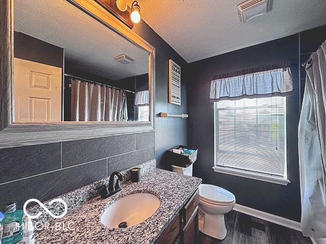 6155 W Bayfront, Mccordsville, IN 46055 - bathroom featuring healthy amount of natural light, toilet, wood finished floors, baseboards, and a textured ceiling