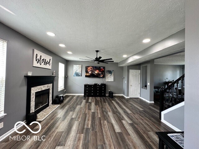 6155 W Bayfront, Mccordsville, IN 46055 - living room with a textured ceiling, wood finished floors, ceiling fan, a fireplace, and baseboards