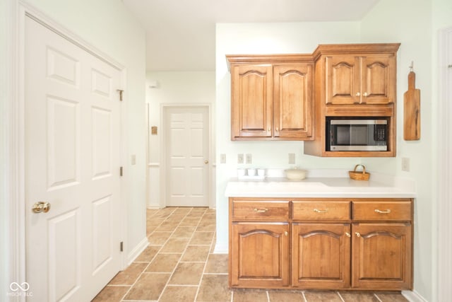 1105 Deer Creek Dr, Anderson, IN 46011 - kitchen with stainless steel microwave, light countertops, and brown cabinetry