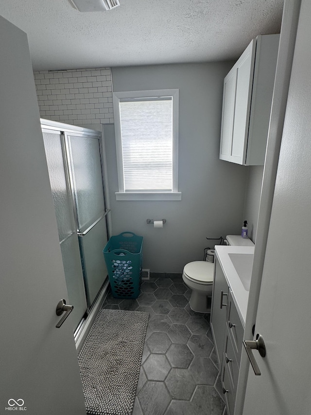 3641 S Rogers St, Bloomington, IN 47403 - bathroom with vanity, a stall shower, a textured ceiling, tile patterned flooring, and toilet