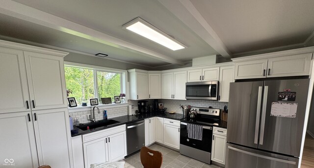 3641 S Rogers St, Bloomington, IN 47403 - kitchen featuring stainless steel appliances, a sink, dark countertops, tasteful backsplash, and beam ceiling
