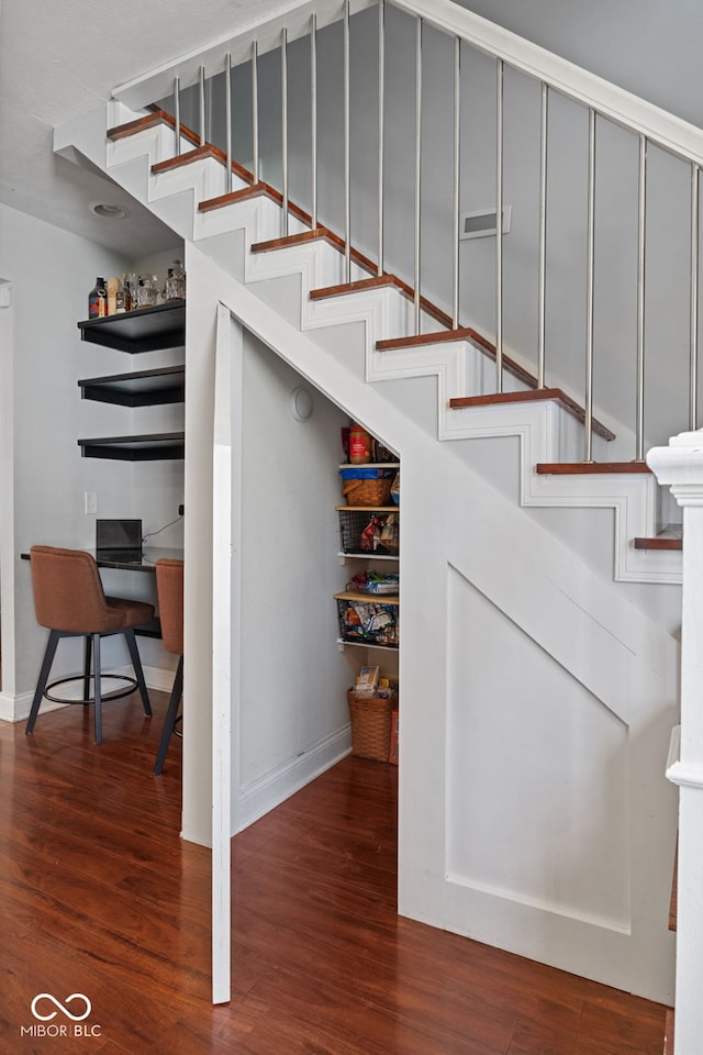 staircase featuring wood finished floors and baseboards