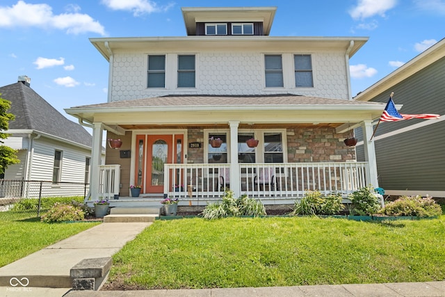 american foursquare style home with covered porch, a front lawn, and stone siding