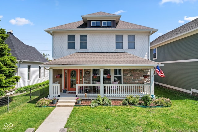 american foursquare style home with covered porch, roof with shingles, and stone siding