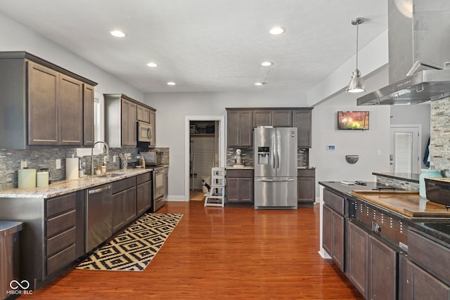 kitchen featuring stainless steel appliances, wall chimney range hood, a sink, tasteful backsplash, and recessed lighting
