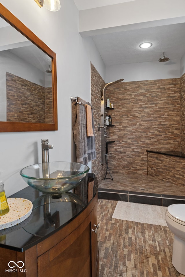 bathroom with tiled shower, a sink, toilet, and recessed lighting