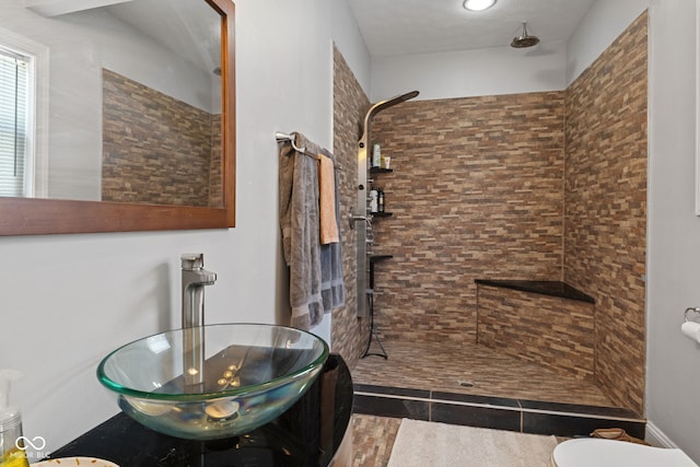 bathroom with tiled shower, toilet, a sink, and tile patterned floors