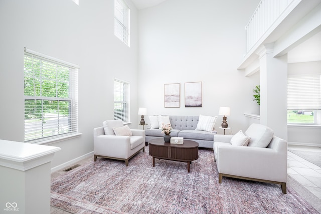 living area with healthy amount of natural light, a high ceiling, baseboards, and tile patterned flooring