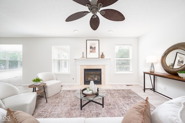living area featuring a fireplace, baseboards, and a ceiling fan