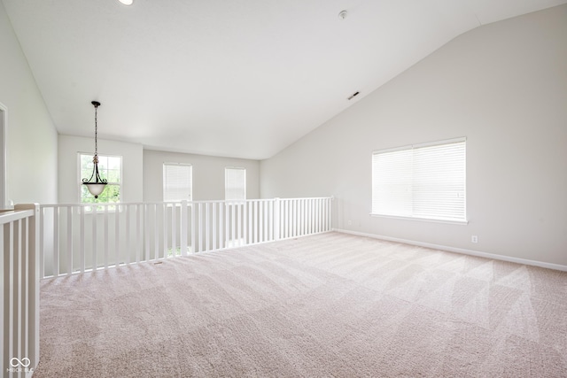 carpeted spare room with lofted ceiling and baseboards