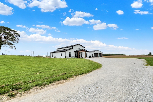view of front of home with gravel driveway, a front lawn, an attached garage, and a view of countryside