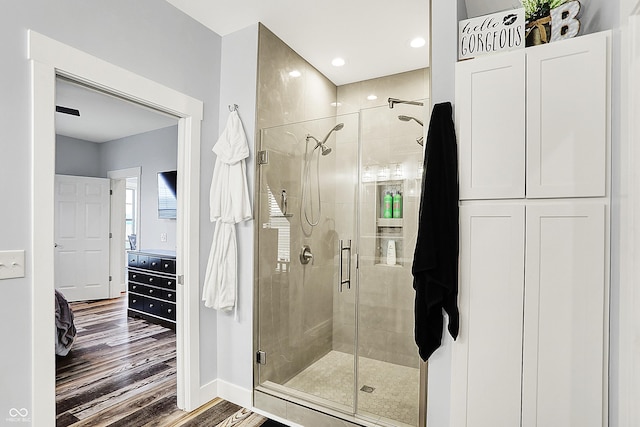 full bathroom with wood finished floors, a stall shower, and baseboards