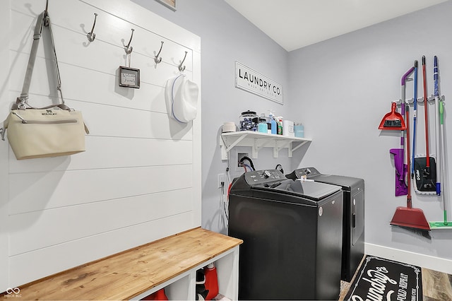 clothes washing area with separate washer and dryer and baseboards