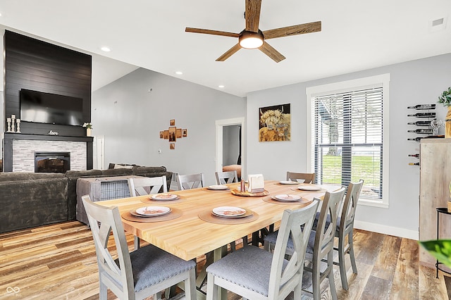 dining room featuring a ceiling fan, light wood-style floors, a fireplace, baseboards, and recessed lighting