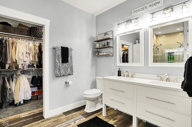 bathroom featuring wood finished floors, a shower stall, a walk in closet, baseboards, and toilet