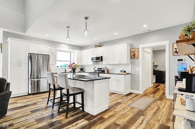 kitchen with appliances with stainless steel finishes, light wood-style flooring, dark countertops, white cabinets, and recessed lighting