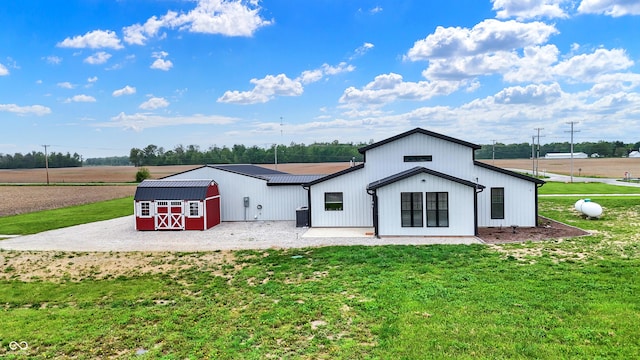 rear view of property featuring a lawn and an outbuilding