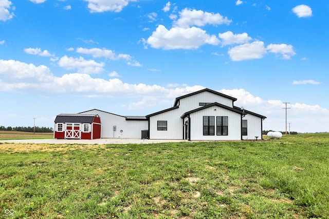modern inspired farmhouse with a front lawn, an outdoor structure, and a barn