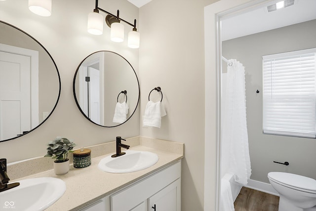 1429 Deloss St, Indianapolis, IN 46201 - bathroom with double vanity, a shower with curtain, toilet, and wood finished floors