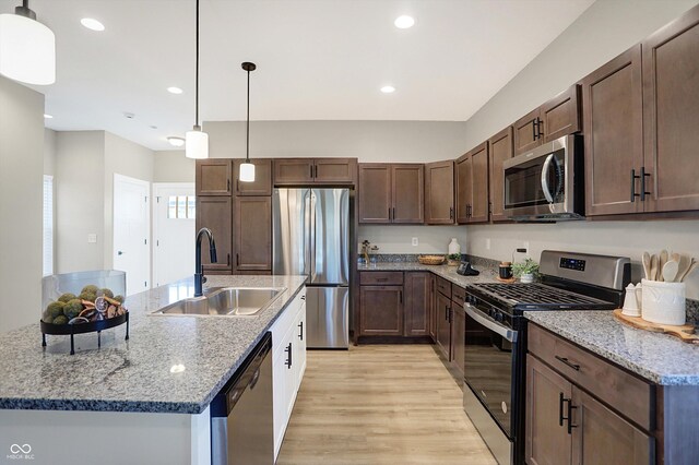 1429 Deloss St, Indianapolis, IN 46201 - kitchen with stainless steel appliances, a sink, light wood-style flooring, hanging light fixtures, and an island with sink