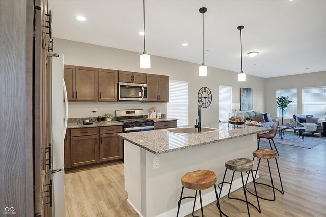 1429 Deloss St, Indianapolis, IN 46201 - kitchen with appliances with stainless steel finishes, a sink, light wood-style floors, open floor plan, and a kitchen breakfast bar