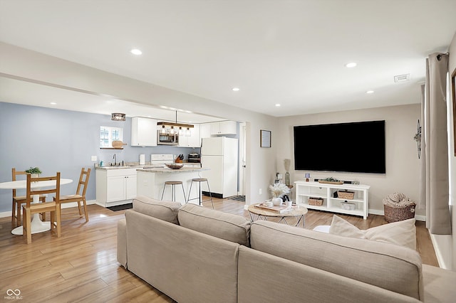 living area featuring light wood finished floors, recessed lighting, and baseboards