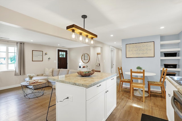 kitchen featuring open floor plan, light wood finished floors, dishwasher, white cabinetry, and recessed lighting