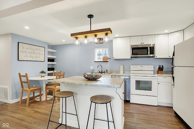 kitchen with stainless steel appliances, a sink, white cabinets, light wood-style floors, and recessed lighting