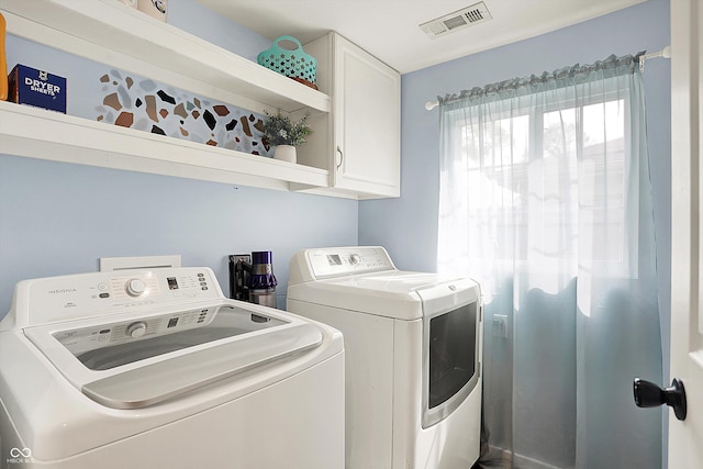 clothes washing area featuring washer and clothes dryer and cabinet space