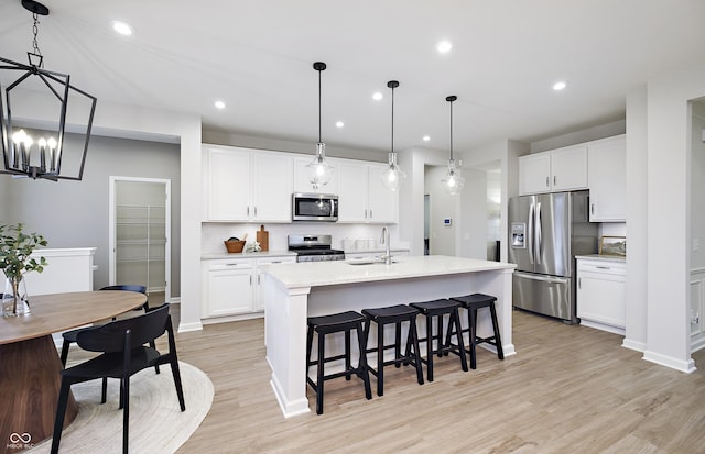 7239 Barrett Dr, Brownsburg, IN 46112 - kitchen featuring appliances with stainless steel finishes, a sink, a kitchen island with sink, a breakfast bar, and light wood finished floors