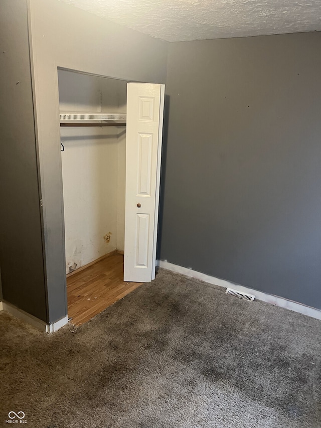 2146 Gent Ave, Indianapolis, IN 46202 - unfurnished bedroom featuring carpet floors, a textured ceiling, wood finished floors, baseboards, and a closet