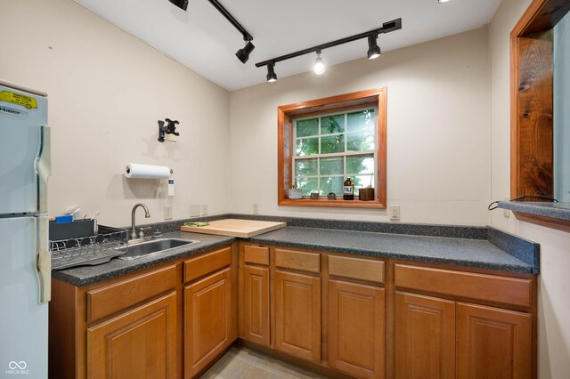 17216 W Hunnicut Rd, Cambridge City, IN 47327 - kitchen featuring freestanding refrigerator, dark countertops, brown cabinetry, and track lighting