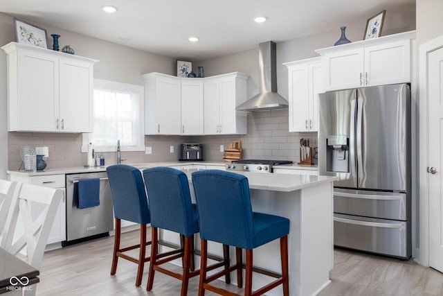3622 S Setting Sun Ln, New Palestine, IN 46163 - kitchen with appliances with stainless steel finishes, wall chimney range hood, light countertops, a kitchen breakfast bar, and a center island