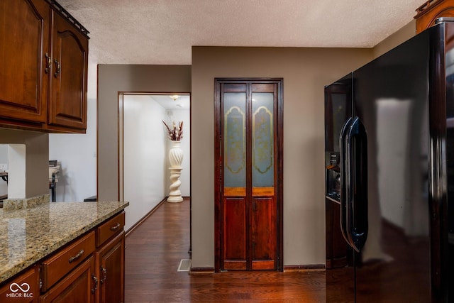 16226 Montrose Ln, Westfield, IN 46074 - kitchen with black refrigerator with ice dispenser, a textured ceiling, dark wood-type flooring, light stone countertops, and baseboards