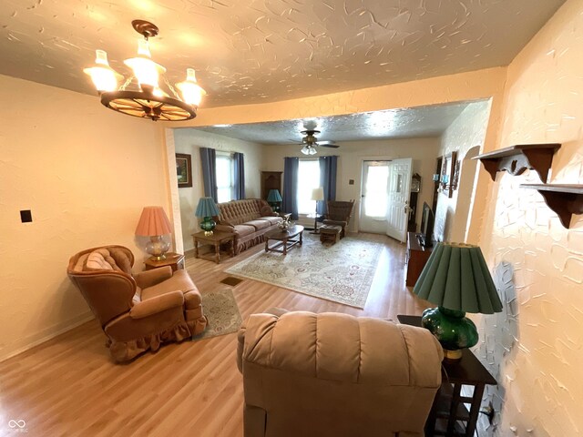 357 S Main St, Spencer, IN 47460 - living area with wood finished floors, a textured wall, a ceiling fan, baseboards, and a chandelier