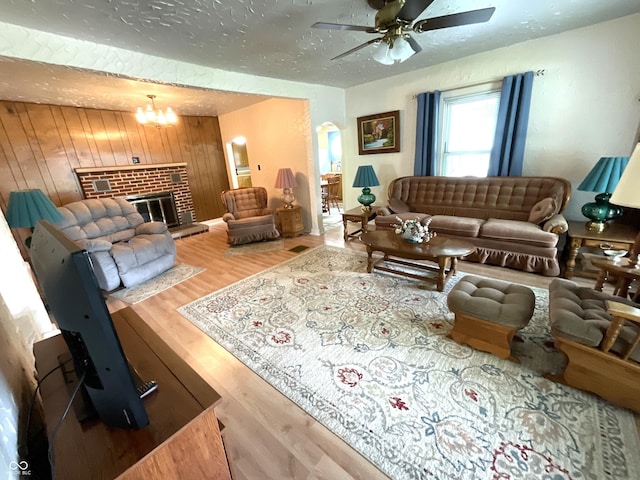 357 S Main St, Spencer, IN 47460 - living area featuring a ceiling fan, wood finished floors, wood walls, a brick fireplace, and a textured ceiling