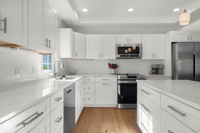 3781 S Station Dr, Columbus, IN 47203 - kitchen with appliances with stainless steel finishes, a raised ceiling, light wood-style floors, white cabinets, and recessed lighting