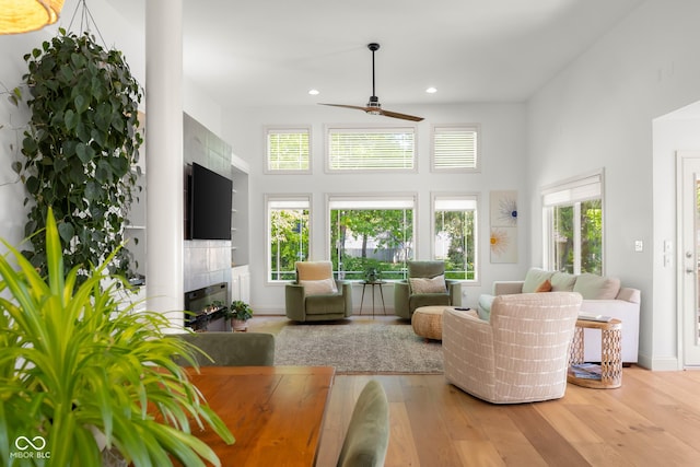 3781 S Station Dr, Columbus, IN 47203 - living room with ceiling fan, a tiled fireplace, wood finished floors, recessed lighting, and a towering ceiling