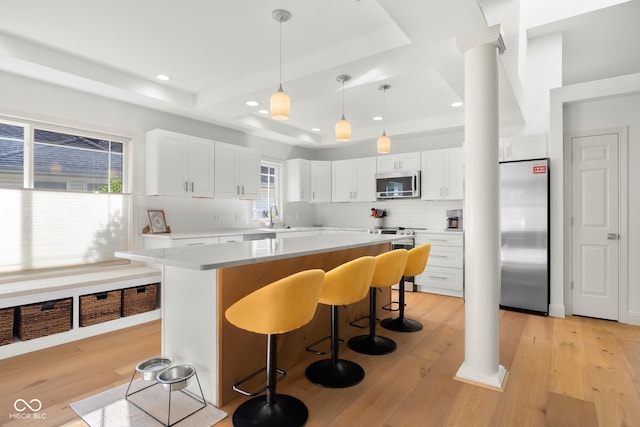 3781 S Station Dr, Columbus, IN 47203 - kitchen featuring appliances with stainless steel finishes, a raised ceiling, a sink, a breakfast bar area, and decorative backsplash
