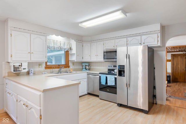 5330 W 56th St, Indianapolis, IN 46254 - kitchen featuring appliances with stainless steel finishes, light wood-type flooring, a peninsula, and decorative backsplash