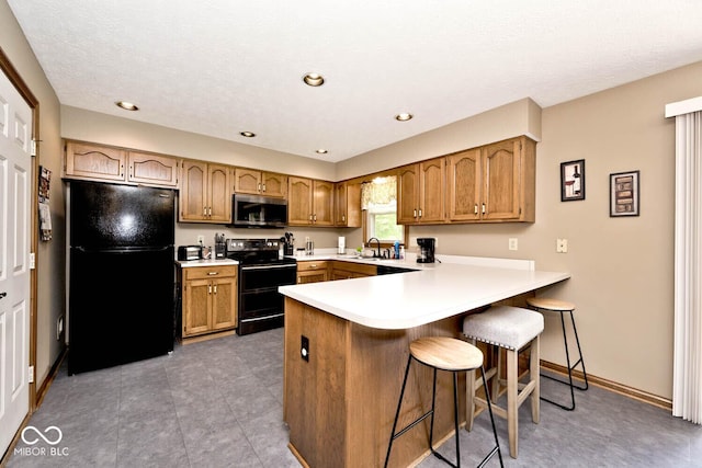 551 Windward Ln, Plainfield, IN 46168 - kitchen featuring black appliances, a peninsula, light countertops, brown cabinets, and a textured ceiling