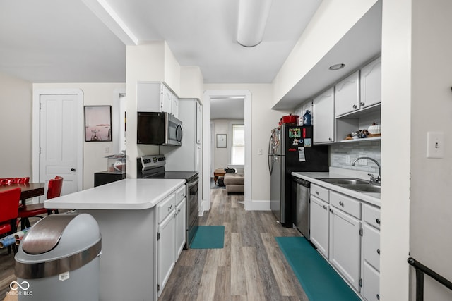 1446 N Illinois St, Indianapolis, IN 46202 - kitchen featuring stainless steel appliances, light wood-style flooring, a peninsula, a sink, and light countertops