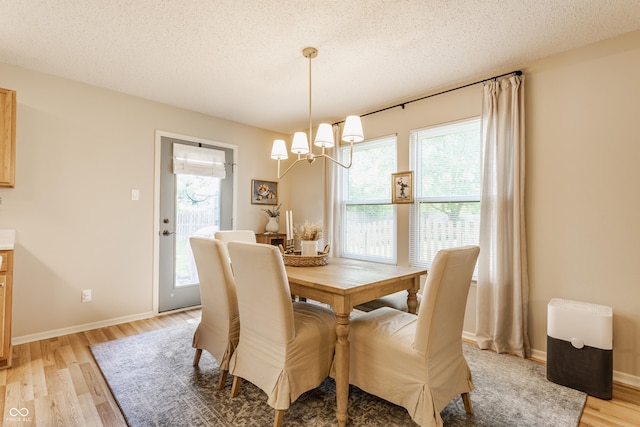 14291 Holly Berry Cir, Fishers, IN 46038 - dining room featuring light wood-style flooring, a chandelier, a textured ceiling, and baseboards