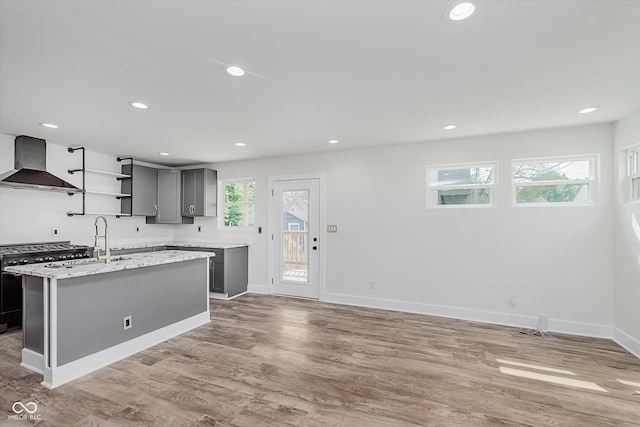 2302 S Pennsylvania St, Indianapolis, IN 46225 - kitchen featuring wall chimney exhaust hood, gray cabinetry, light wood finished floors, open shelves, and stainless steel gas range oven