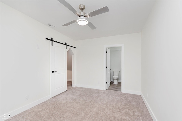 2302 S Pennsylvania St, Indianapolis, IN 46225 - unfurnished bedroom with a barn door, carpet floors, baseboards, and ensuite bathroom
