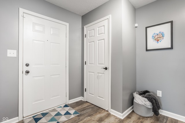 foyer entrance featuring dark wood-style floors, baseboards, and a textured ceiling