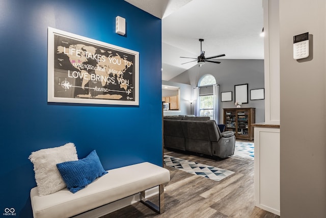 living area featuring wood finished floors, a ceiling fan, and vaulted ceiling