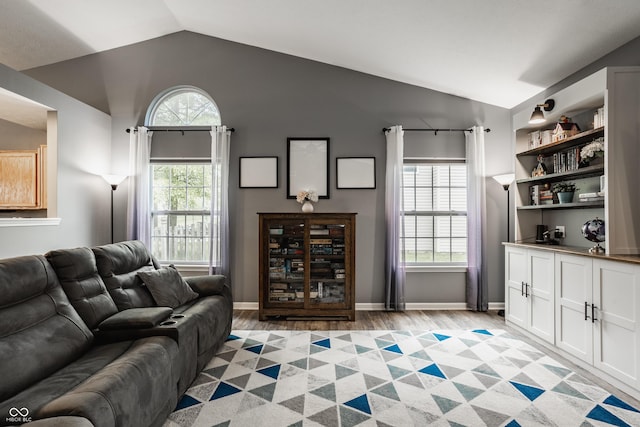 living room with lofted ceiling, light wood-style flooring, and baseboards